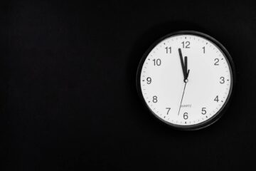 black round analog wall clock on black background