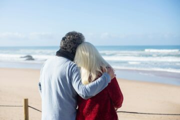 back view of a romantic elderly couple standing on the beach