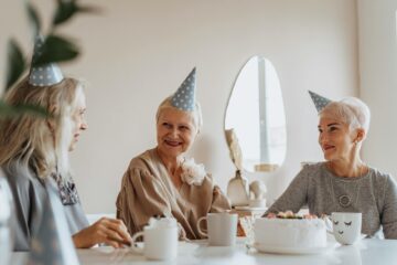 photograph of elderly women with party hats having a conversation